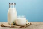 Bottiglia di latte e bicchiere con panna fresca su tessuto di yuta