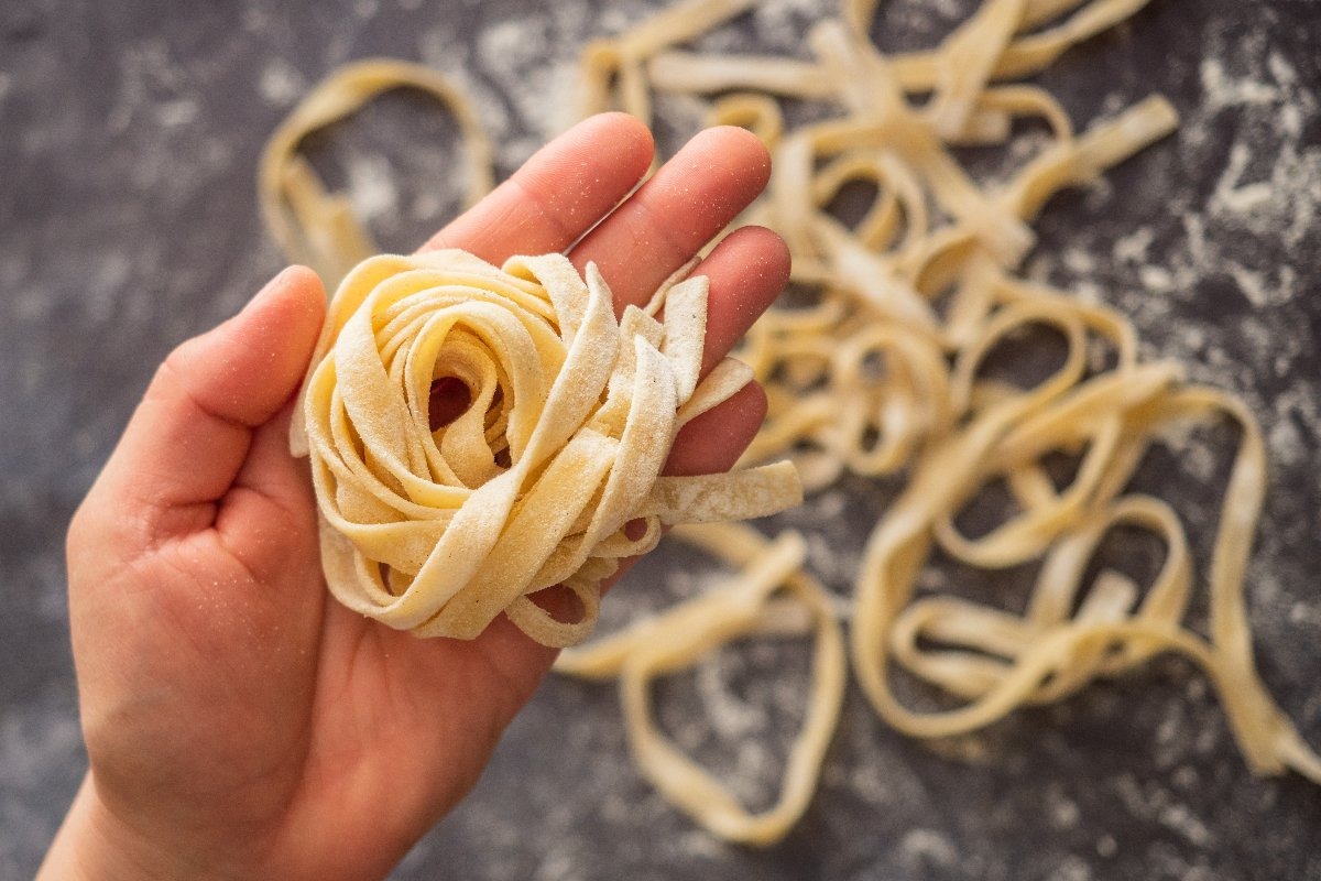 Vista dall'alto mano che mostra nido di tagliatelle fatte in casa