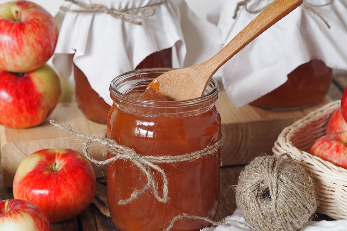Barattolo di marmellata di mele aperto con cucchiaino di legno all'interno