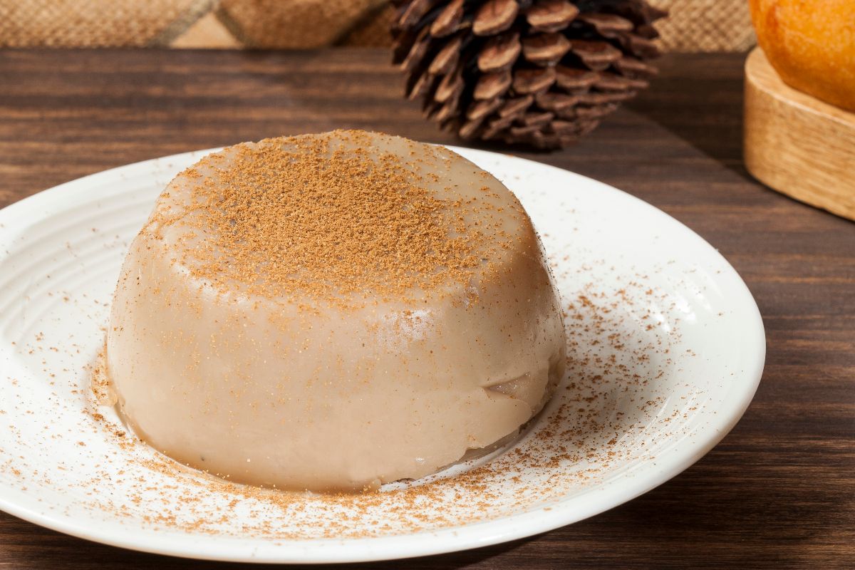 Budino alla cannella su piatto bianco decorato con cannella in polvere