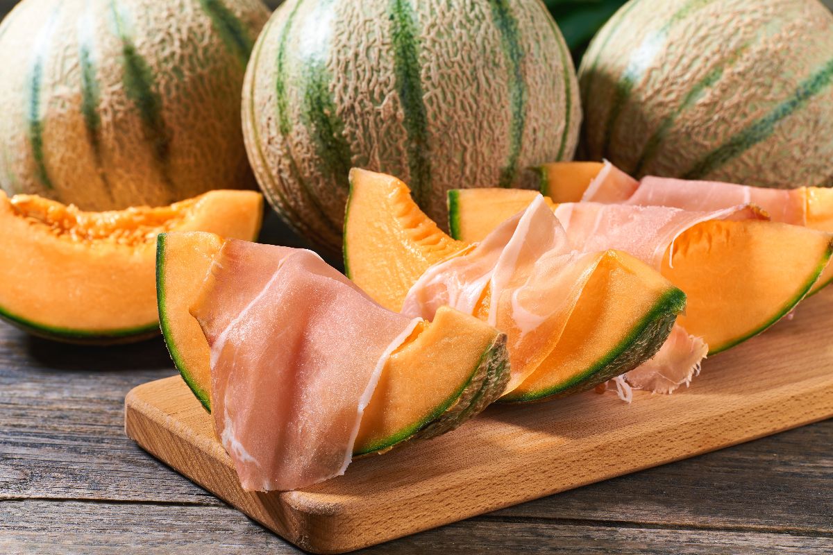 Tagliere di legno con fette di melone e prosciutto crudo