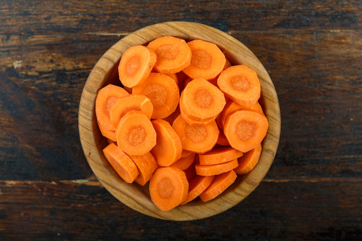 Carrots cut into slices in wooden bowl top view