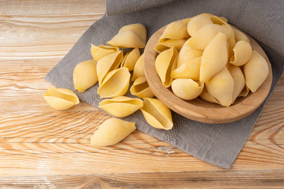 Piatto di legno con conchiglioni di pasta da cuocere