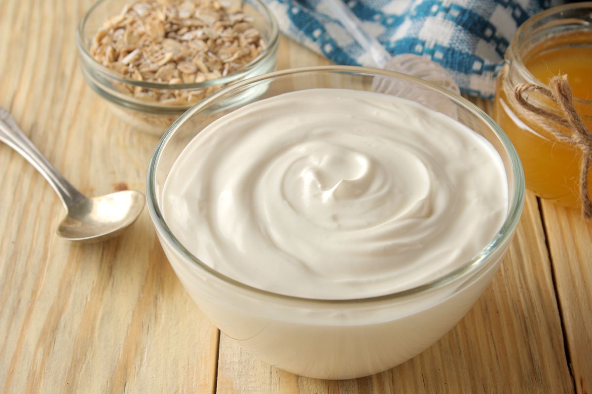 Yogurt in a glass bowl with teaspoon and other ingredients