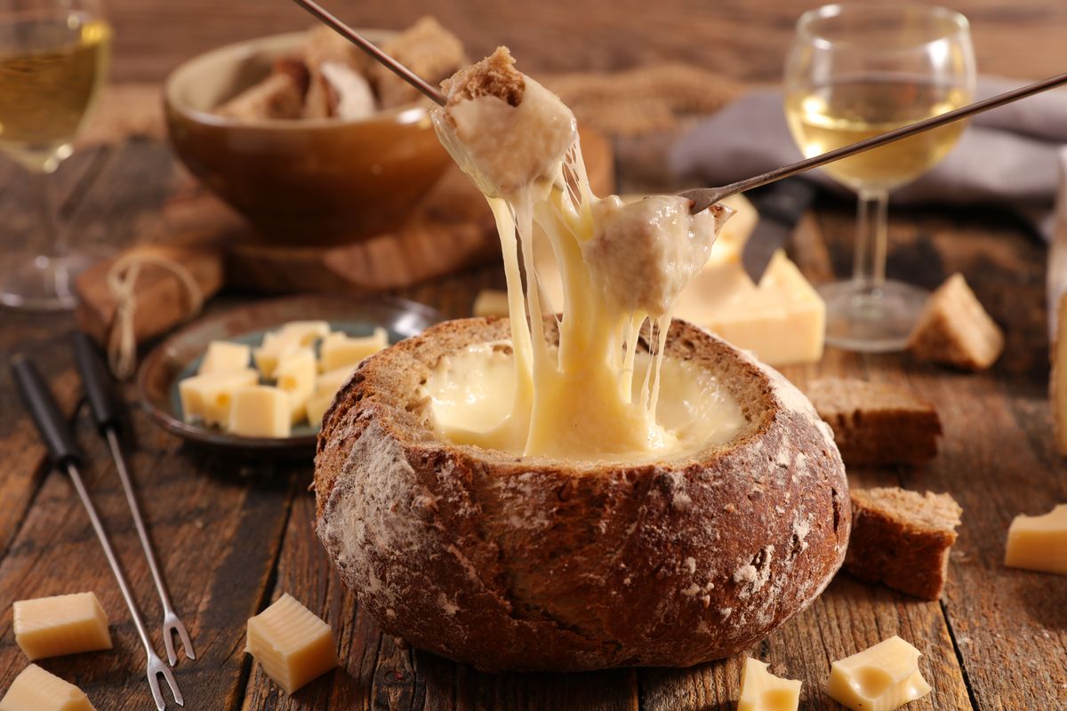 Una deliziosa fonduta di formaggio con forcelle di immersione ricoperti di  formaggio fuso circondato da diversi tipi di pane e patate Foto stock -  Alamy