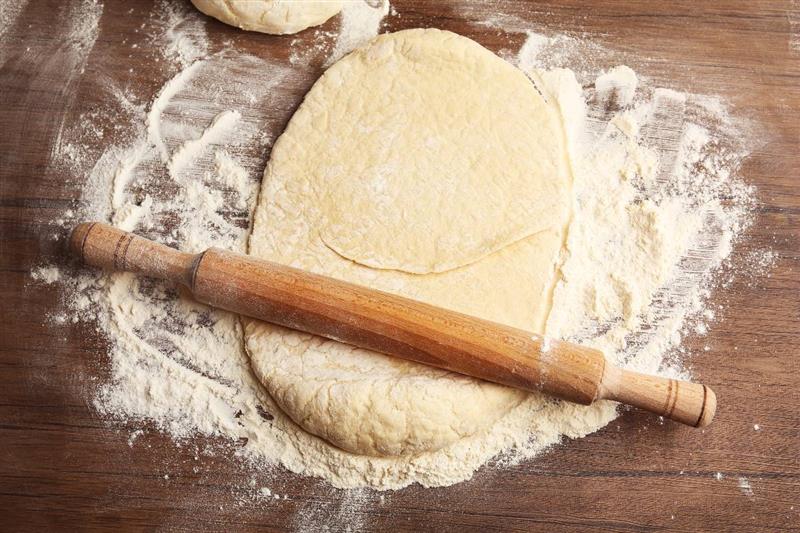 Impasto steso con il mattarello su spianatoia infarinata