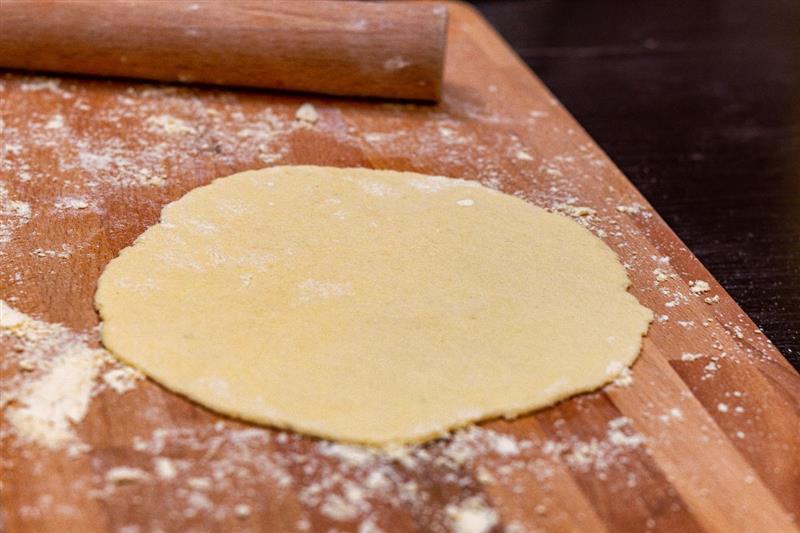 Impasto steso su tagliere di legno infarinato con mattarello