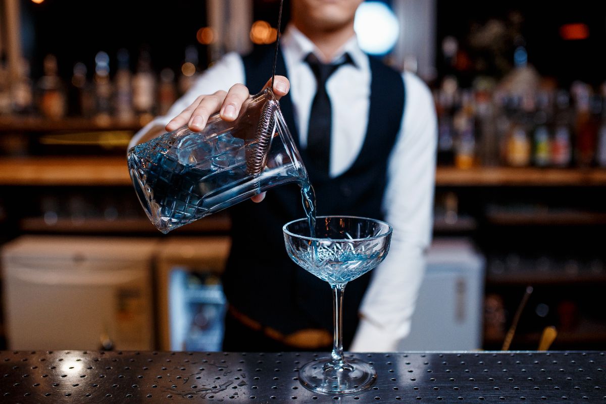 Barman che prepara cocktail angelo azzurro in coppa da champagne