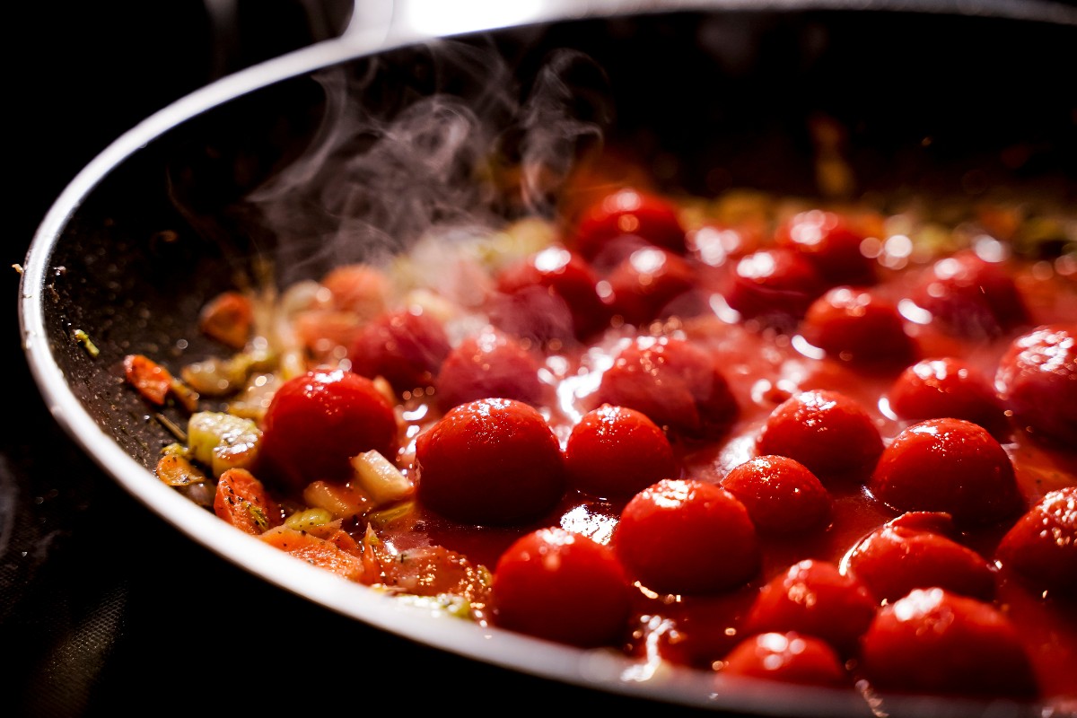 Cooking cherry tomatoes in a pan with oil and onion