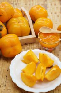 Primo piano con piatto di cachi, cachi e marmellata sullo sfondo