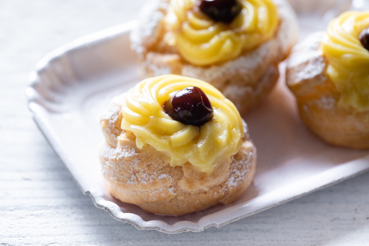 San Giuseppe zeppole stuffed with custard and black cherry placed on a paper tray