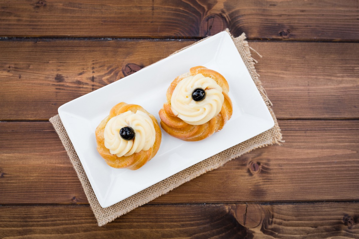 Zeppole di San Giuseppe seen from above filled with custard and black cherries in syrup