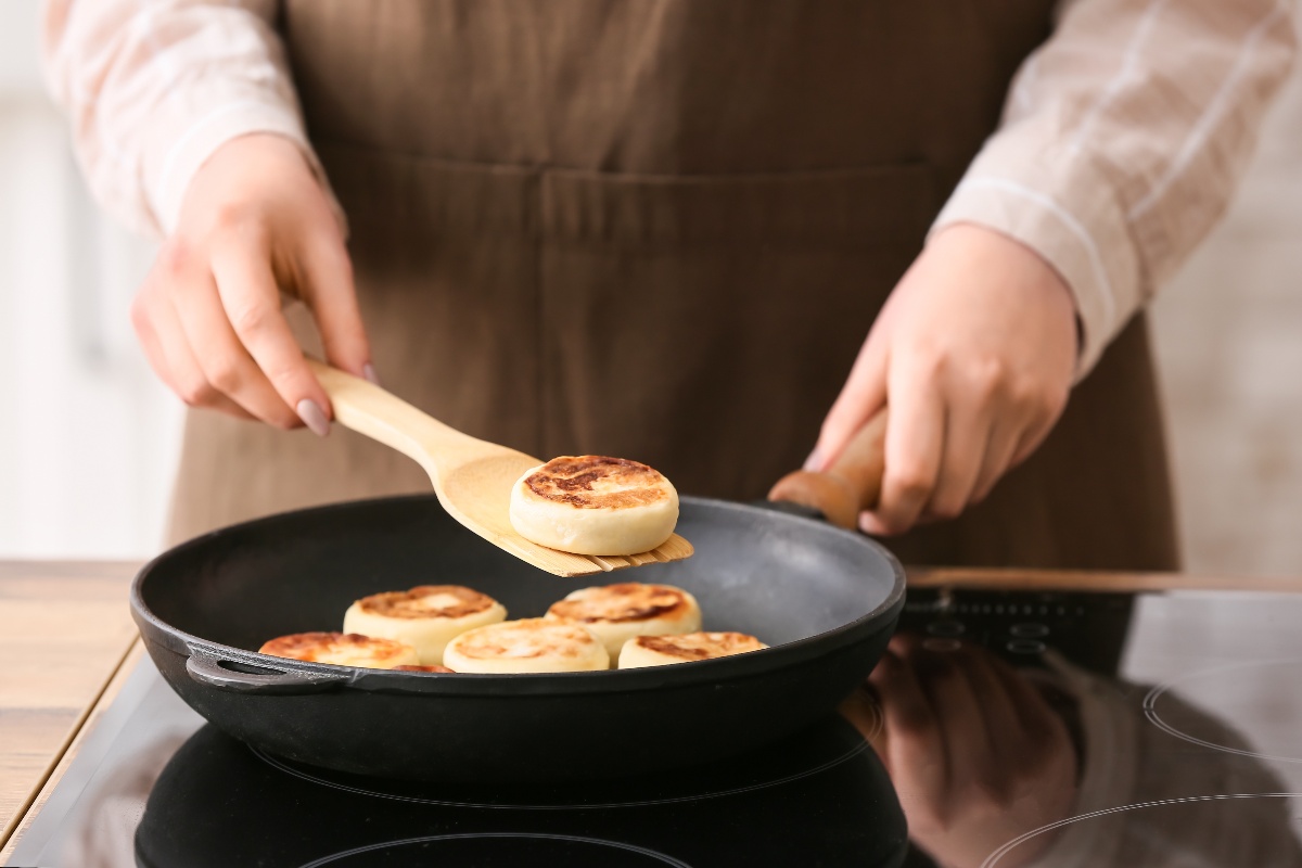 Woman flipping pancakes in an iron pan.