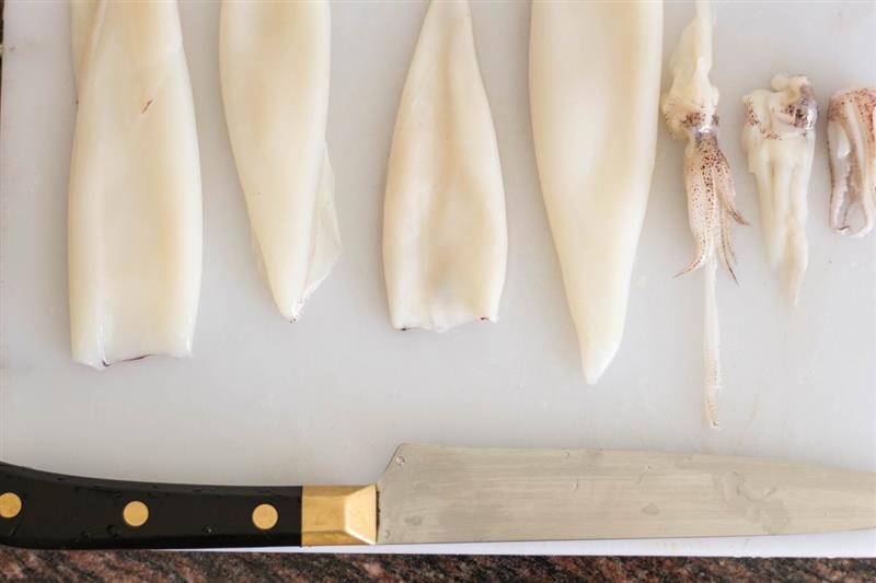 Calamari puliti su tagliere di plastica con coltello