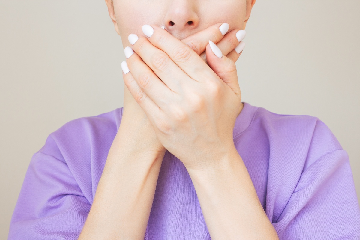 Una donna si copre la bocca con le mani, nascondendo il viso