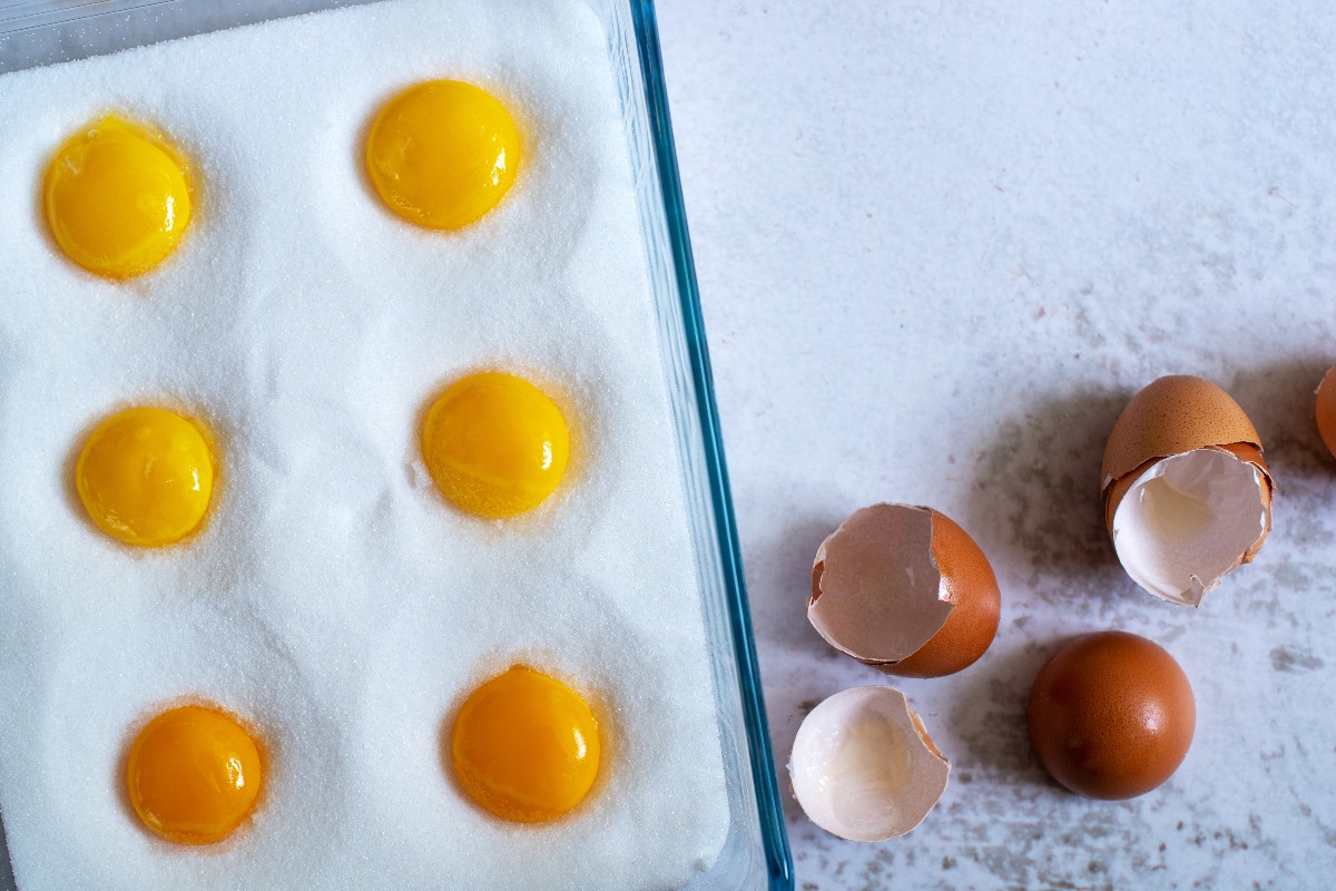 Salt and sugar in a glass baking dish with recesses for egg yolks