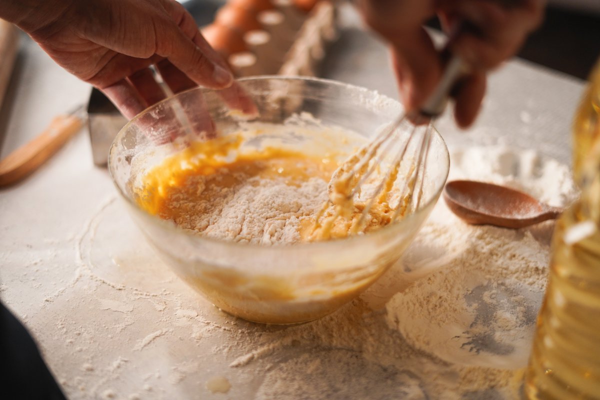 Bowl with egg mixture to which flour is added, worked with a hand whisk.