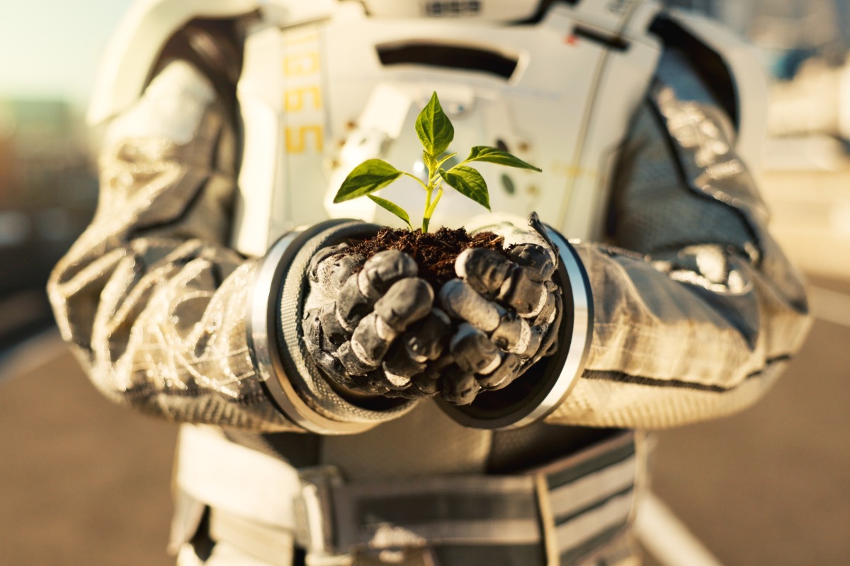 Un astronauta con una piantina da coltivare tra le mani