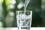 Acqua frizzante mentre viene versata in un bicchiere di vetro