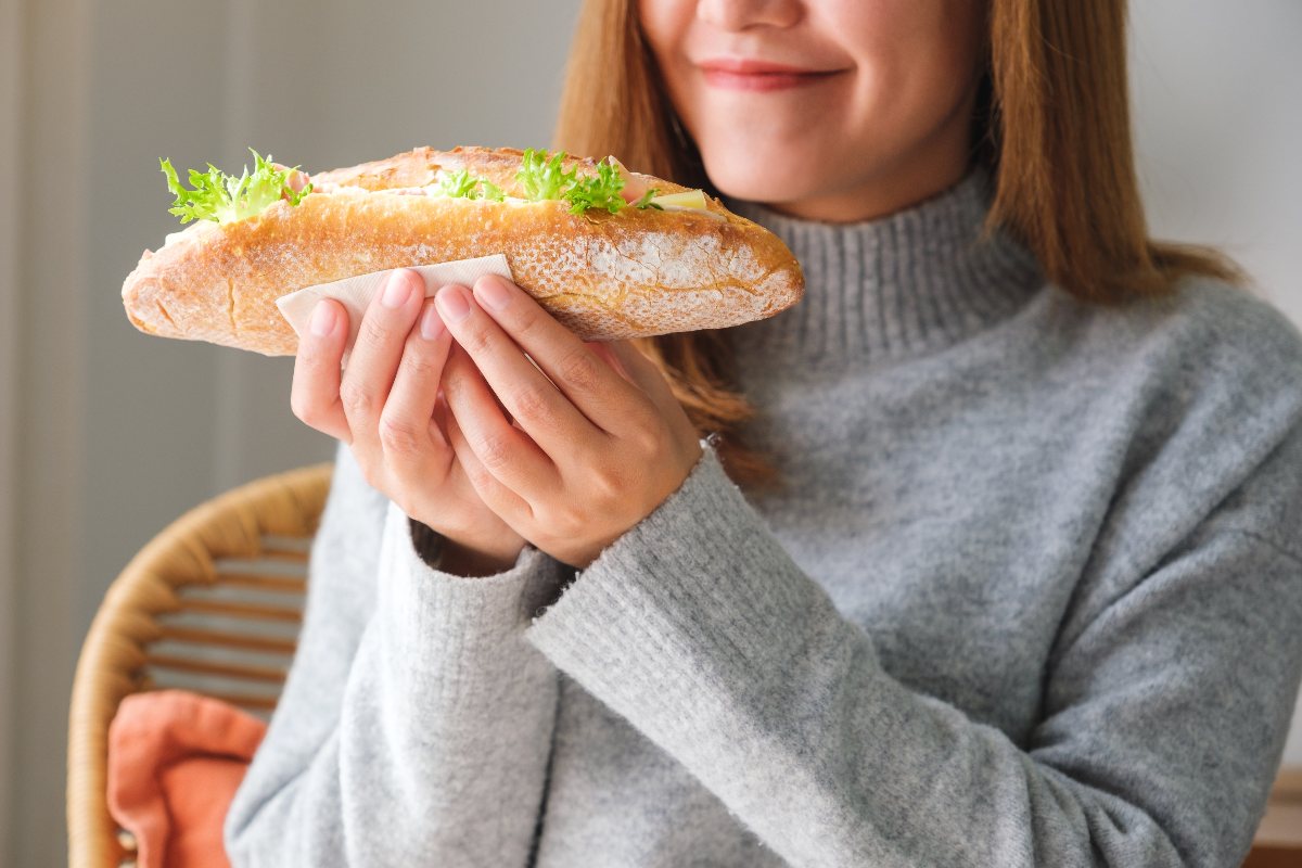 Una giovane donna sta gustando un panino imbottito