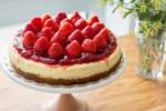 Torta cheesecake alle fragole decorata con fragole fresche su alzatina