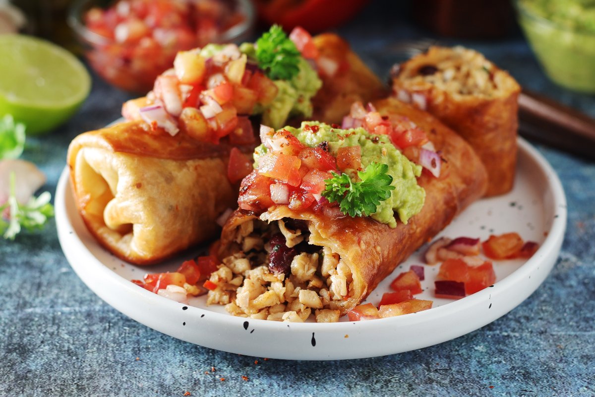 Tortillas ripiena di carne servita con pomodori e guacamole nota come chimichanga