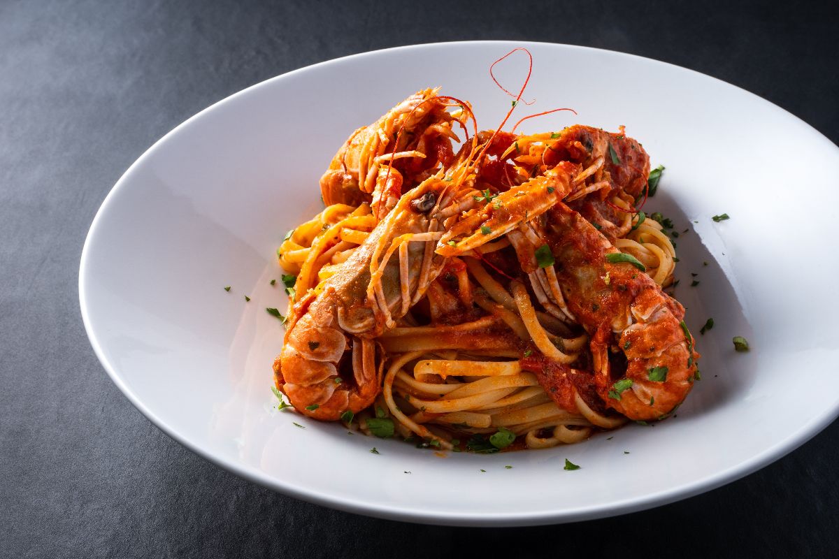 Piatto di pasta tipo spaghetti con sugo di pomodoro e scampi