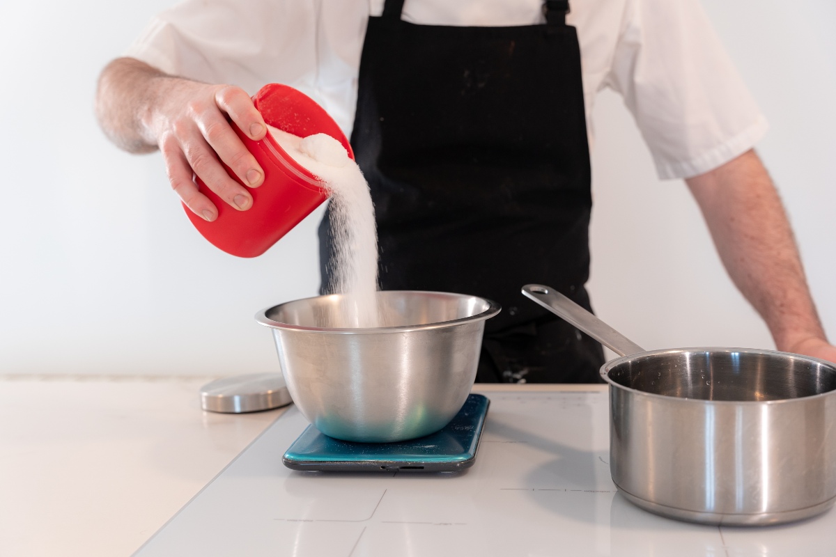 Versare lo zucchero nella ciotola del bagnomaria per preparare meringa svizzera
