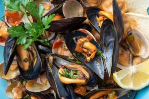 Sauté di cozze e vongole decorato con limone a fettine e prezzemolo fresco.