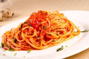 Piatto di spaghetti al pomodoro con basilico a julienne