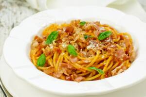 Piatto di pasta con pomodoro, pancetta e basilico