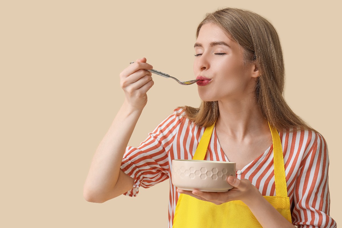 Ragazza che gusta con piacere una calda zuppa