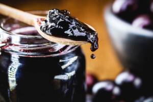 Cucchiaino di legno con marmellata posato sul vasetto della marmellata