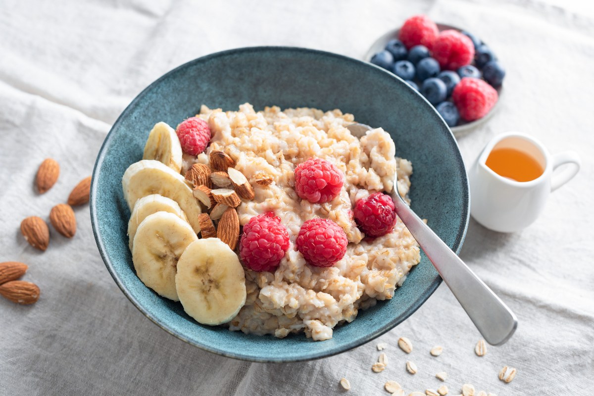 Vista dall’alto di una ciotola di porridge con mandorle, banana e lamponi.