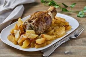 Piatto con stinco di maiale cotto al forno con le patate