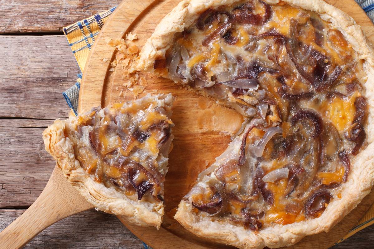 Vista dall'alto di fetta di torta salata alle cipolle caramellate appena tagliata