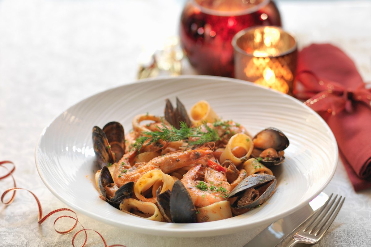Calamarata di mare: piatto di pasta con gamberi e cozze su un tavolo natalizio.