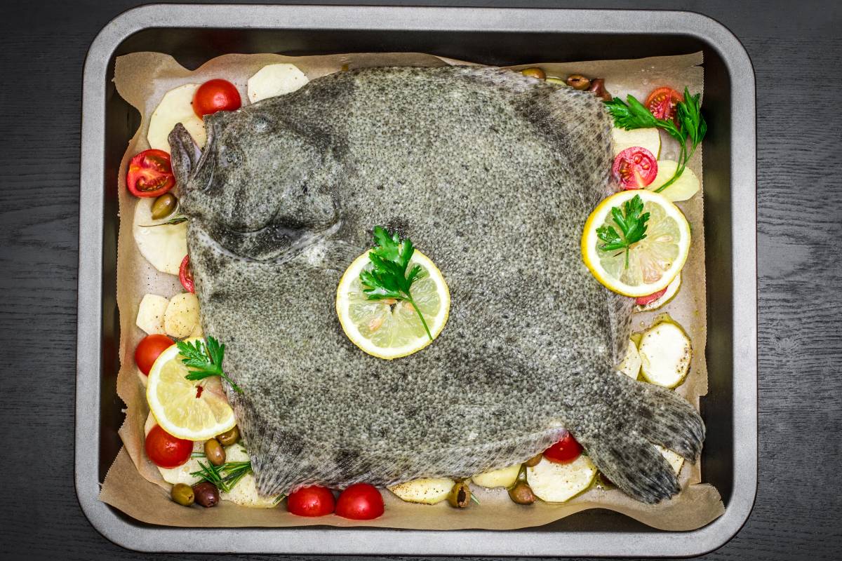 Pesce rombo su teglia da forno con patate, pomodorini e limone a fette