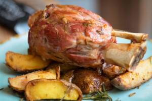 Stinco di maiale al forno con patate su piatto