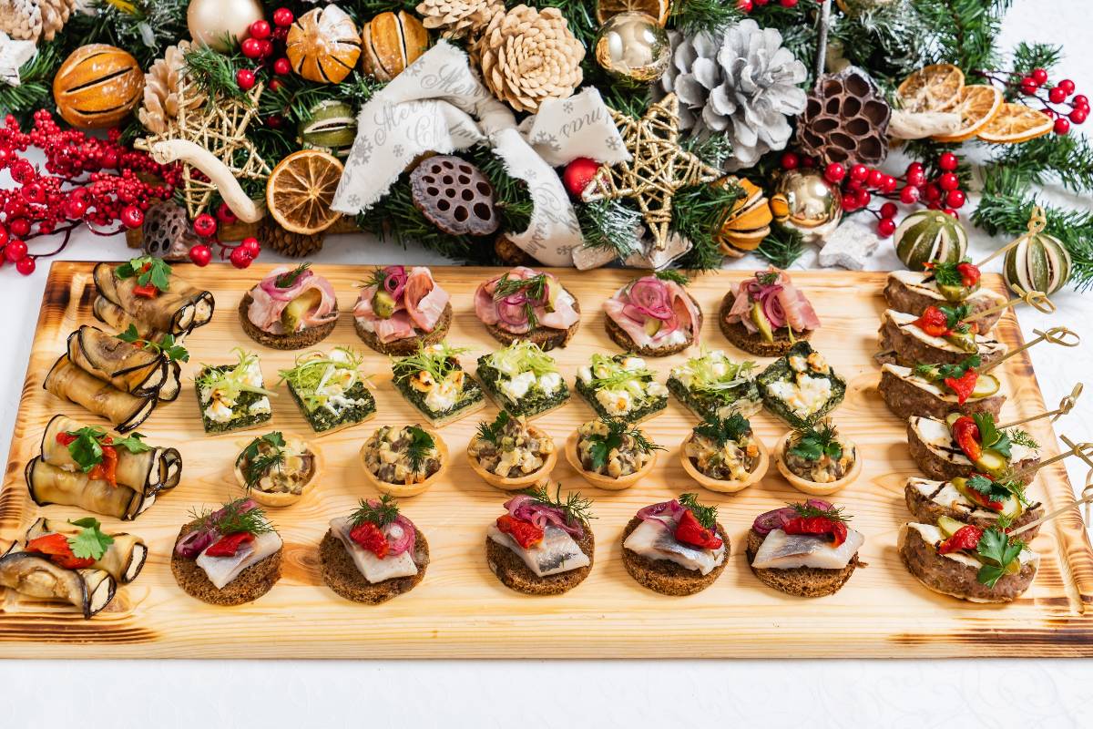 Tagliere di tartine creative per l'apericena, su tavolo con addobbi natalizi.