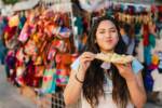 Gusto messicano: ragazza in un mercato locale mentre assaggia un chicharron.