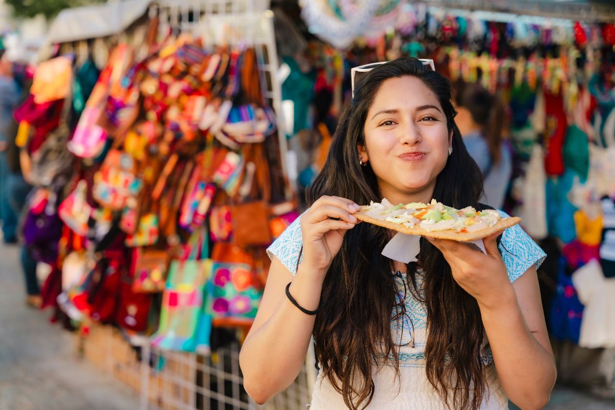 Gusto messicano: ragazza in un mercato locale mentre assaggia un chicharron.