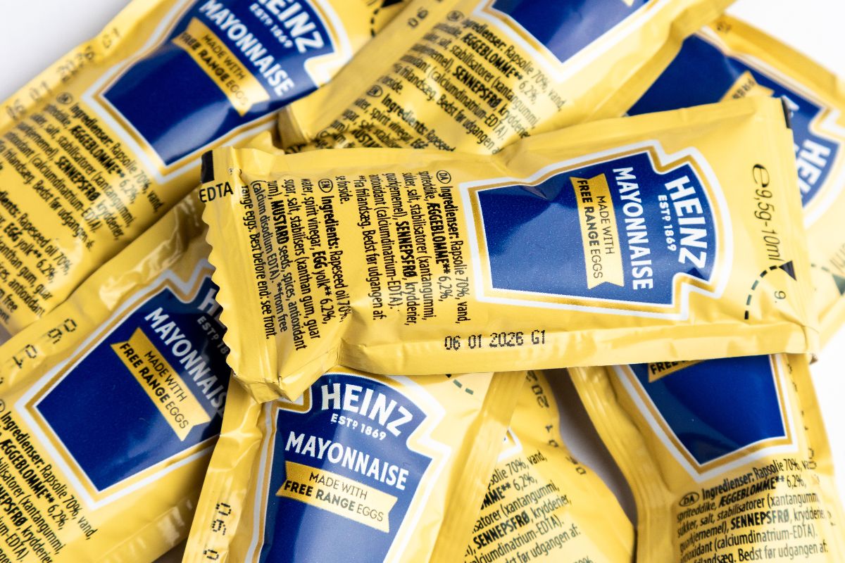 Bustine di maionese sparse casualmente su una superficie bianca.