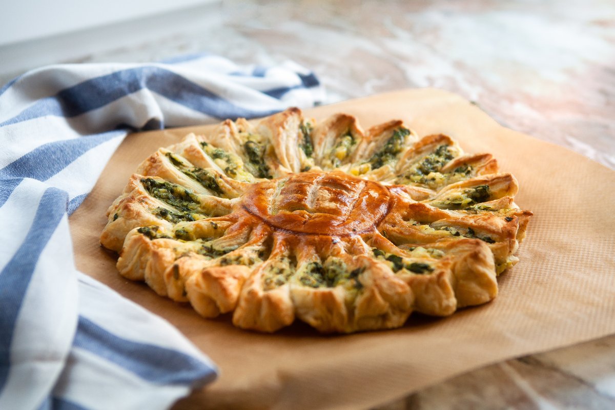 Girasole di pasta sfoglia ripieno con ricotta e spinaci su foglio di carta forno