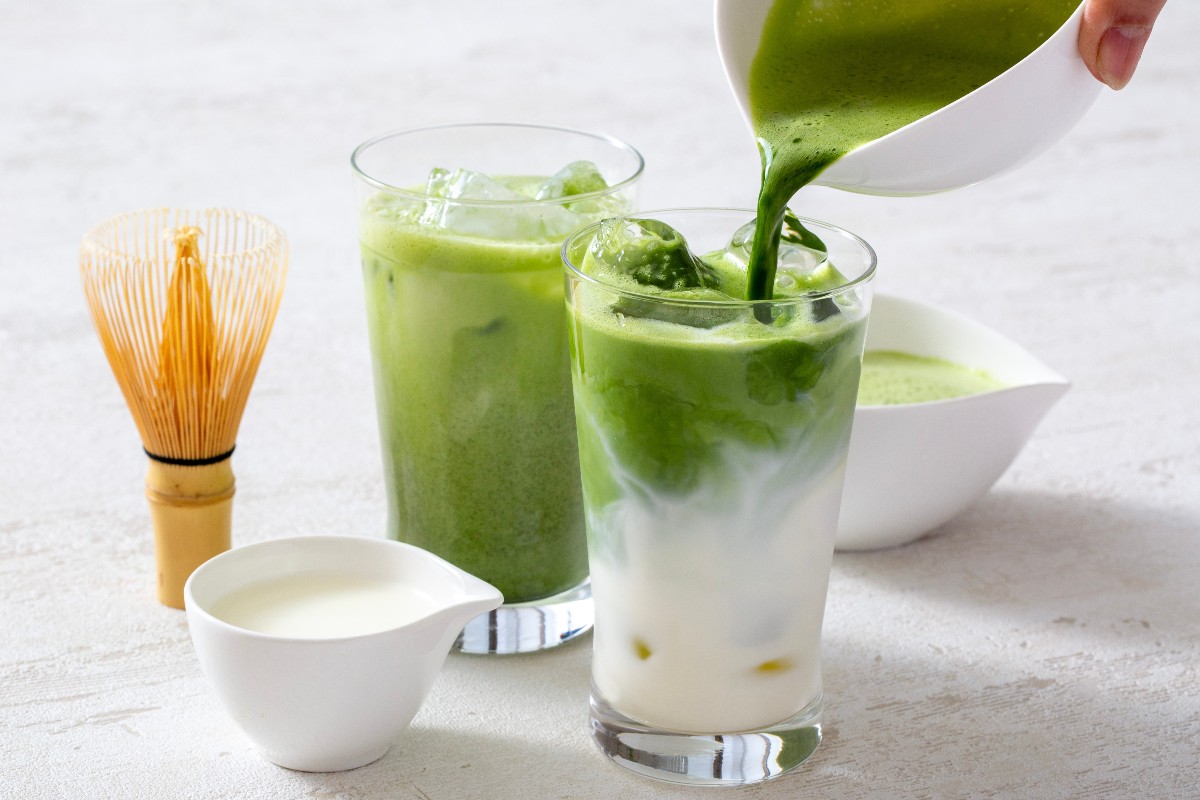 The matcha versato su latte montato con vicino frustino e ciotola con latte