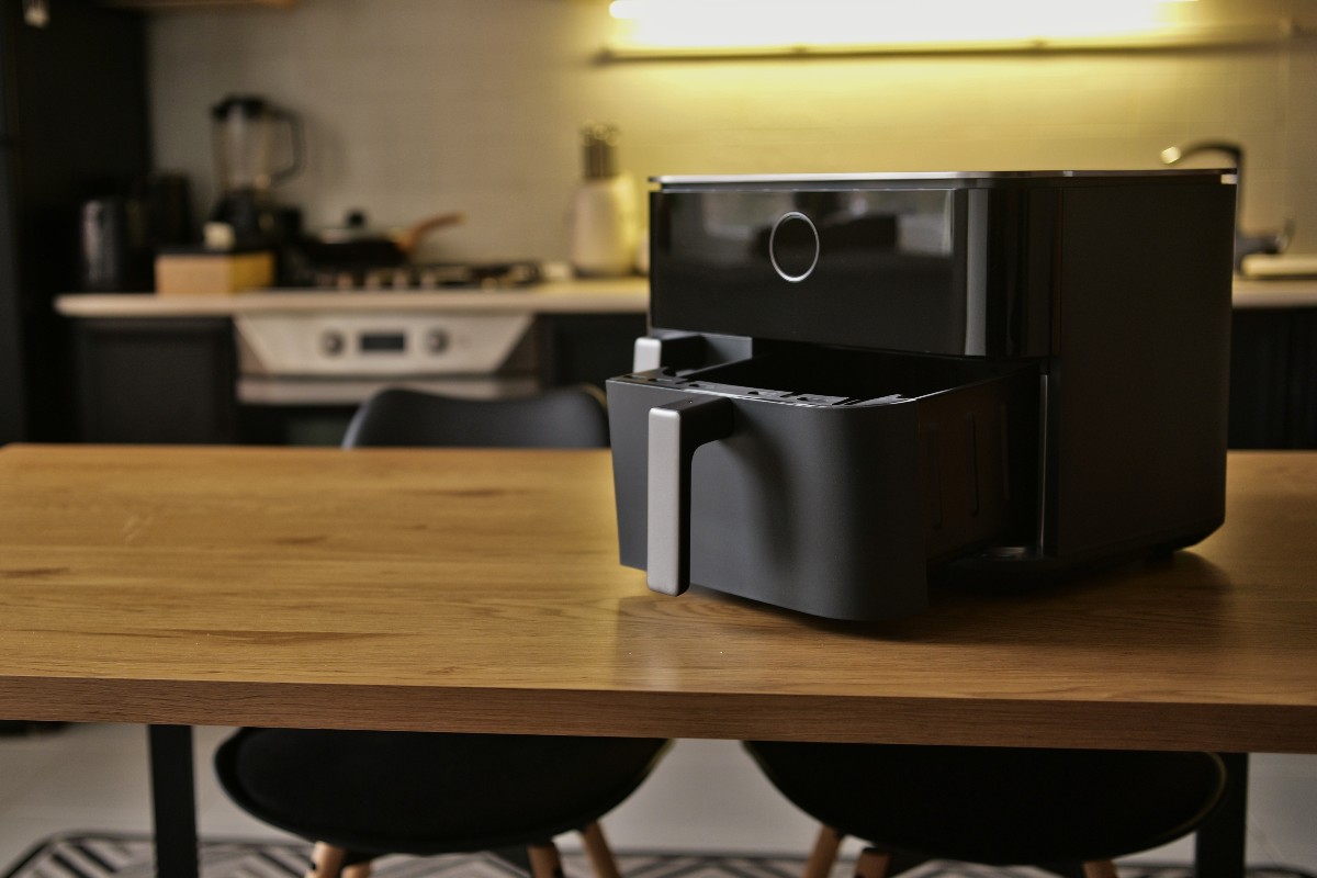 Una friggitrice ad aria a doppio cestello nera appoggiata sul tavolo della cucina.