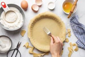 Base per crostata rivestita con pasta frolla bucherellata con forchetta